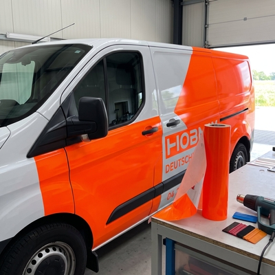 Pellen van uitgesneden belettering in oranje fluorescerende Oracal 6510 vinyl op werktafel in signmakerij