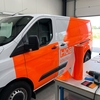 Pellen van uitgesneden belettering in oranje fluorescerende Oracal 6510 vinyl op werktafel in signmakerij
